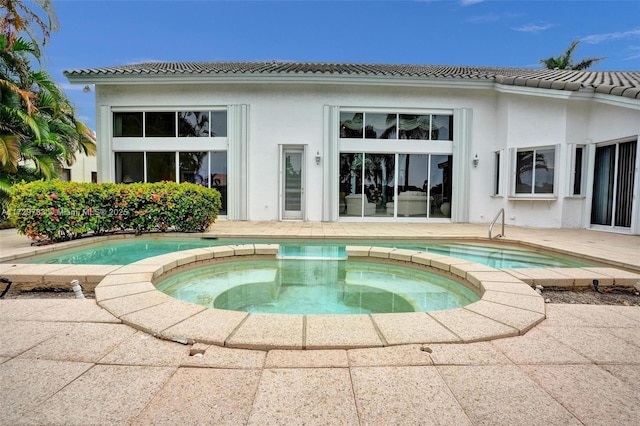 back of property featuring a pool with hot tub and a patio