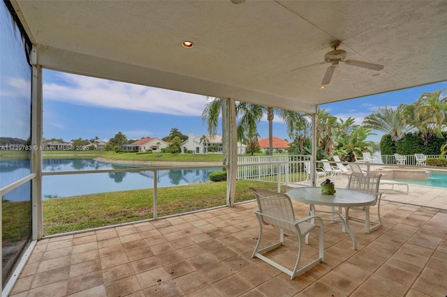 unfurnished sunroom featuring ceiling fan and a water view