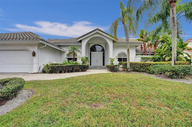 mediterranean / spanish home featuring a garage and a front lawn