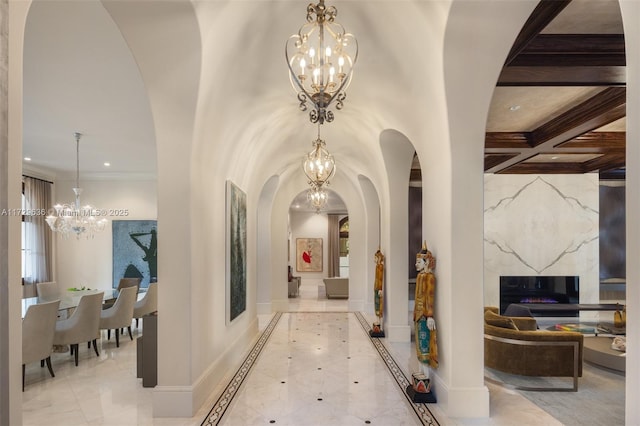 corridor featuring a notable chandelier, coffered ceiling, beamed ceiling, and ornamental molding