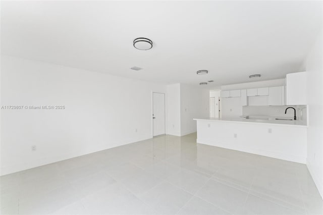 unfurnished living room featuring light tile patterned flooring and sink