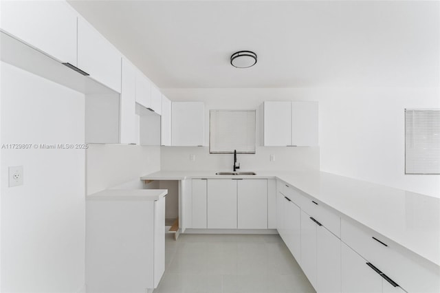 kitchen featuring light tile patterned floors, sink, and white cabinets