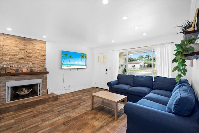 living room with crown molding, a stone fireplace, and hardwood / wood-style floors