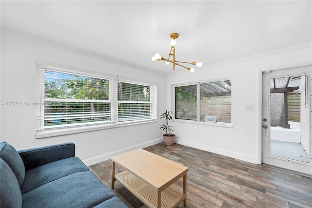 living room featuring a notable chandelier, ornamental molding, hardwood / wood-style floors, and a wealth of natural light