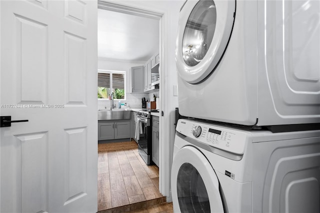 laundry room with stacked washing maching and dryer, sink, and ornamental molding