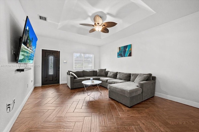 living room featuring parquet flooring, ceiling fan, and a raised ceiling