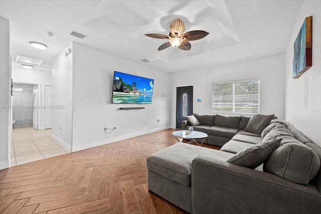 living room featuring ceiling fan, light parquet flooring, and a tray ceiling