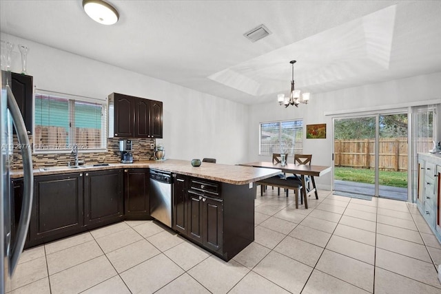 kitchen with kitchen peninsula, decorative light fixtures, backsplash, stainless steel appliances, and dark brown cabinetry