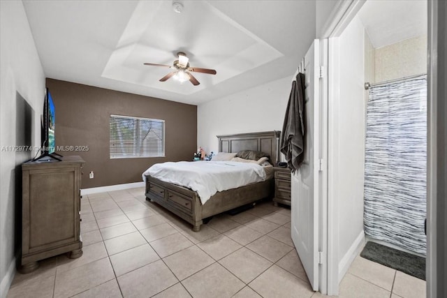 bedroom with ceiling fan, a raised ceiling, and light tile patterned flooring