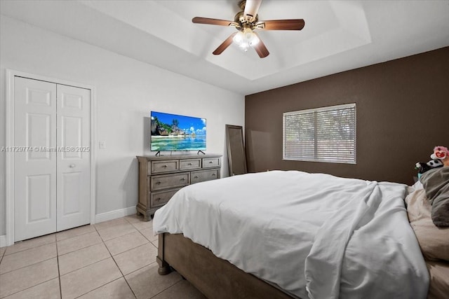 tiled bedroom featuring a closet, ceiling fan, and a tray ceiling