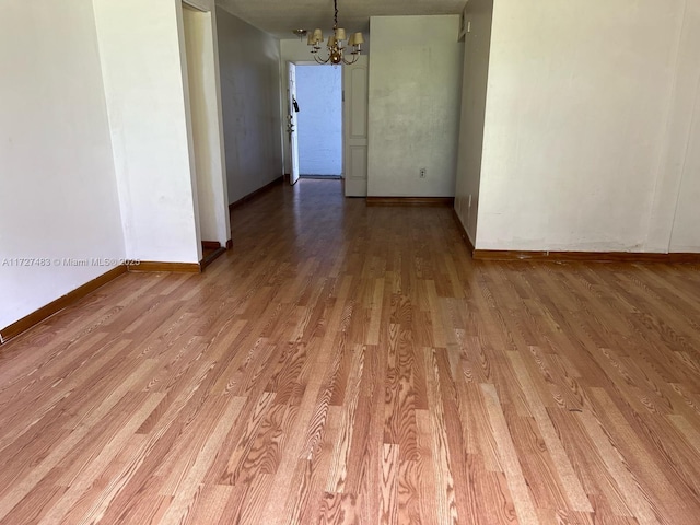 empty room featuring light hardwood / wood-style floors and an inviting chandelier