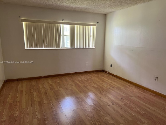 unfurnished room featuring light wood-type flooring and a textured ceiling