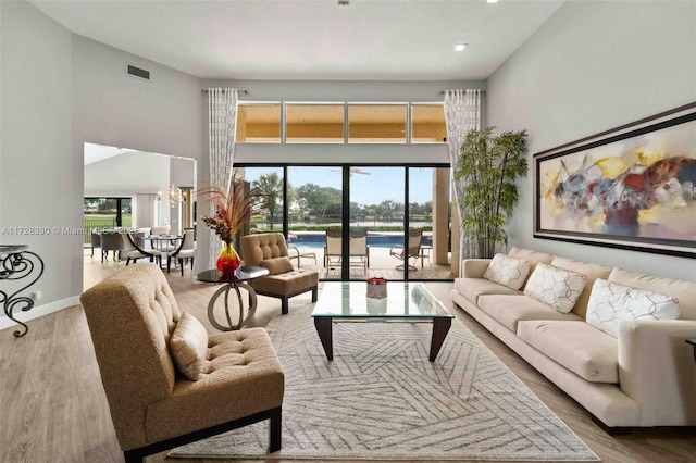 living room with hardwood / wood-style flooring, a chandelier, and a towering ceiling