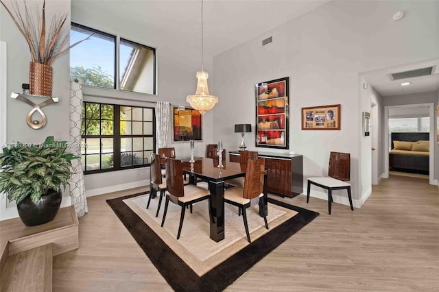 dining room with light wood-type flooring and high vaulted ceiling