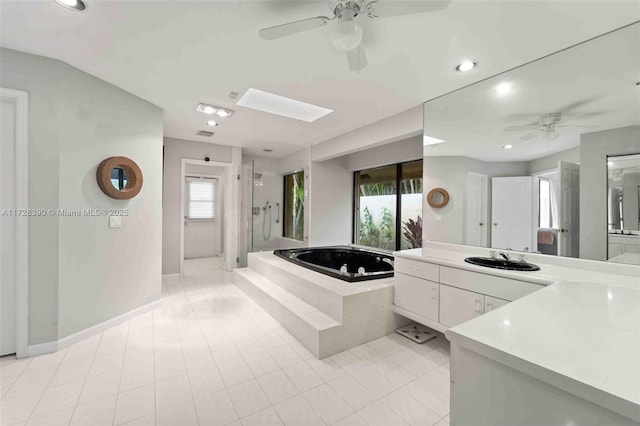 bathroom with a skylight, independent shower and bath, plenty of natural light, and vanity