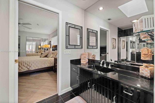 bathroom featuring tile patterned flooring, a shower with door, vanity, a skylight, and ceiling fan