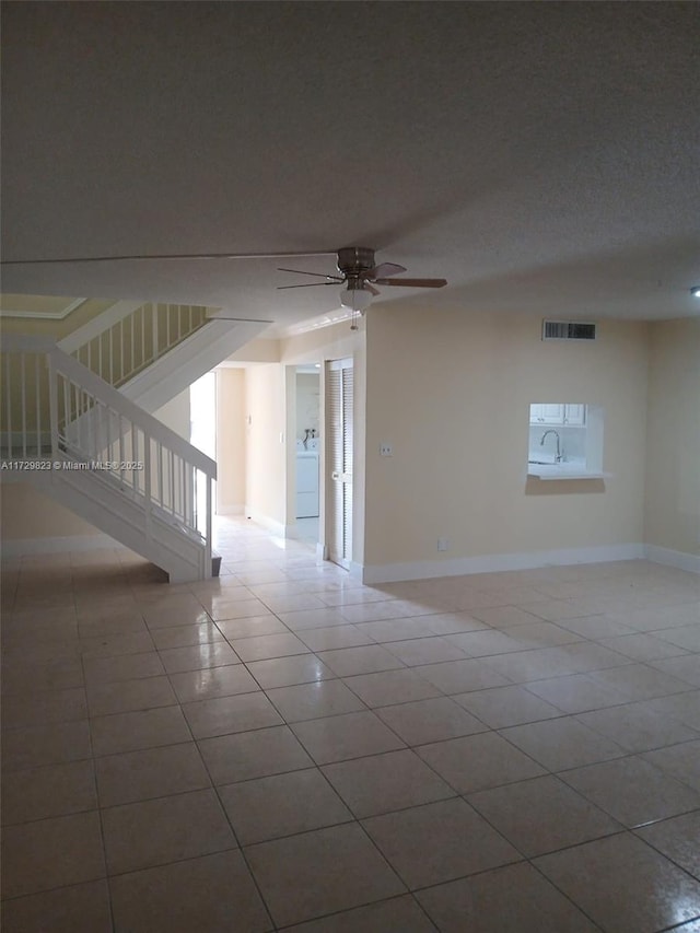 spare room with washer / clothes dryer, light tile patterned floors, a textured ceiling, and ceiling fan