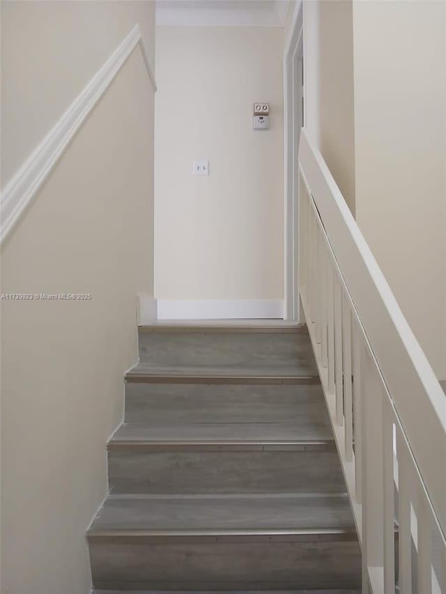 stairs with hardwood / wood-style flooring and ornamental molding