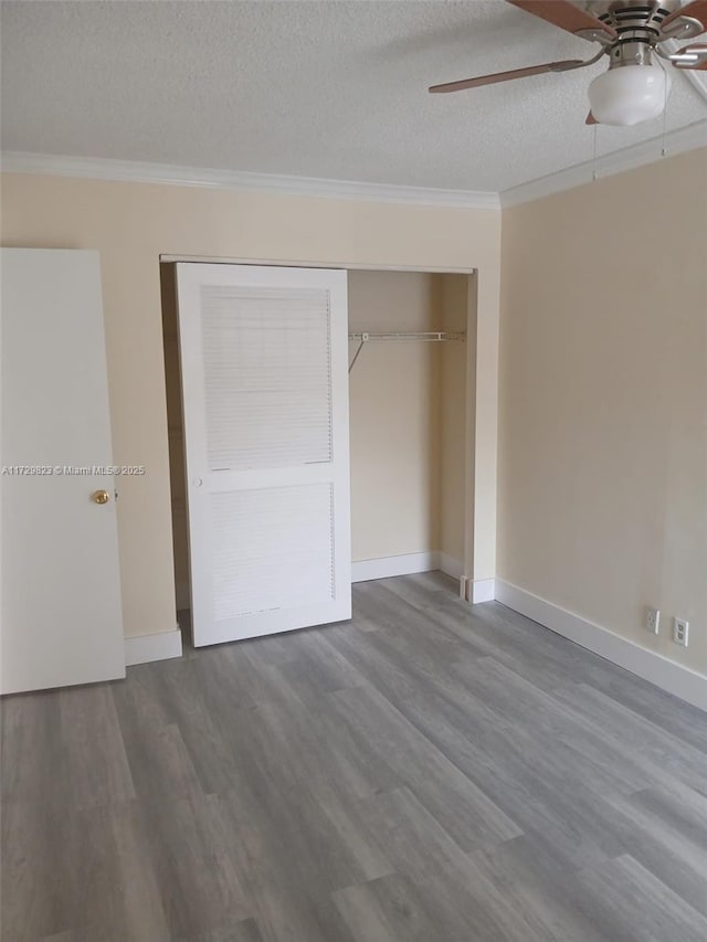 unfurnished bedroom featuring crown molding, ceiling fan, wood-type flooring, a textured ceiling, and a closet