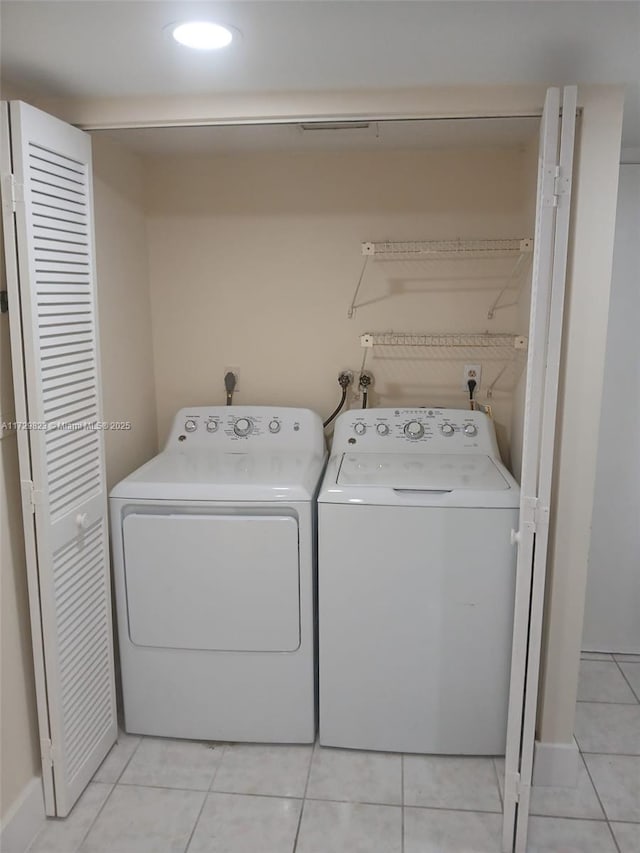 clothes washing area featuring light tile patterned flooring and washer and clothes dryer