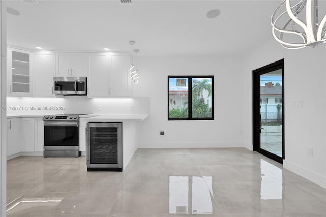 kitchen featuring stainless steel appliances, plenty of natural light, white cabinets, and wine cooler