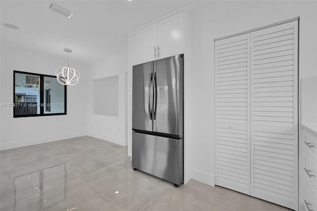 kitchen with a chandelier, hanging light fixtures, light tile patterned floors, stainless steel refrigerator, and white cabinets