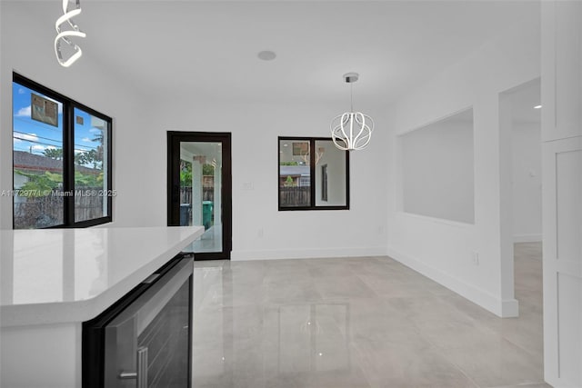 unfurnished dining area featuring beverage cooler and a notable chandelier