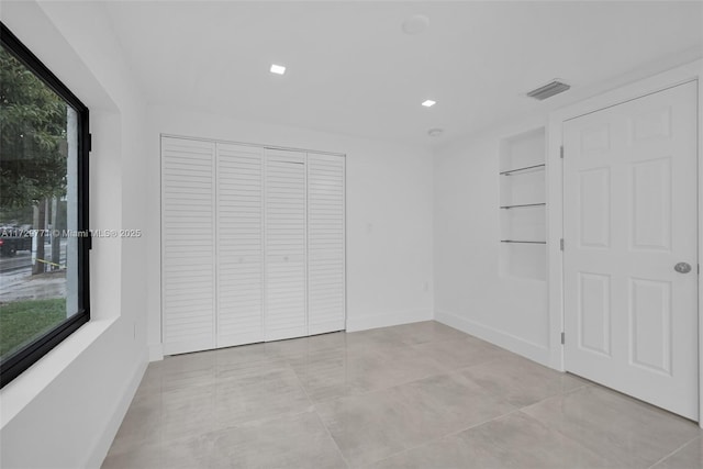 spare room with built in shelves and a wealth of natural light