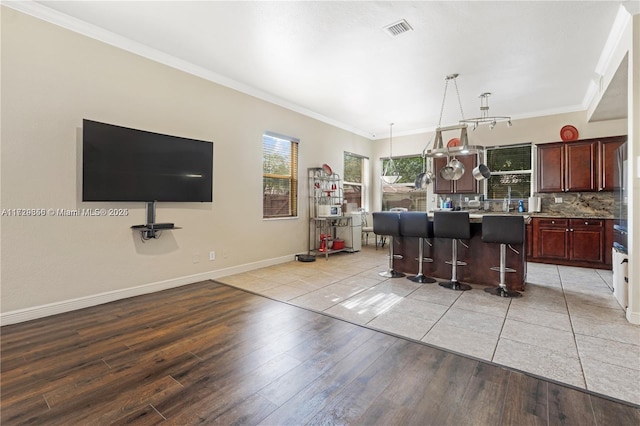 kitchen with a kitchen island, a kitchen breakfast bar, decorative backsplash, light hardwood / wood-style floors, and crown molding