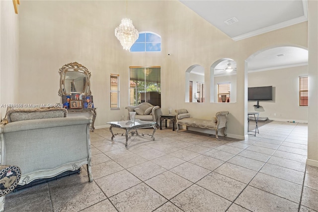 tiled living room featuring a high ceiling, ornamental molding, and ceiling fan with notable chandelier