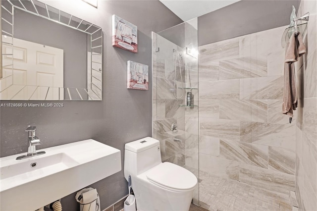 bathroom featuring tiled shower, sink, and toilet