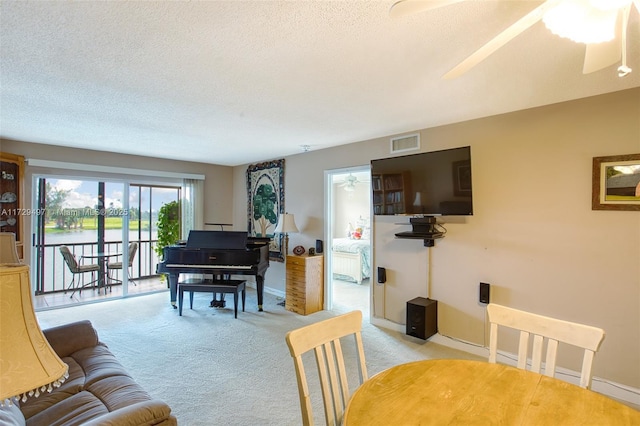 living room featuring ceiling fan, a textured ceiling, and light carpet