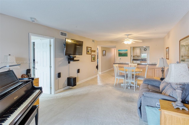 living room with ceiling fan, light colored carpet, and a textured ceiling