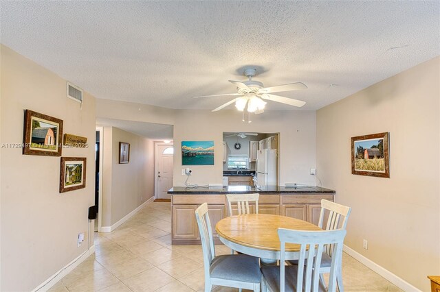 kitchen with light brown cabinetry, a textured ceiling, white fridge, light colored carpet, and electric panel