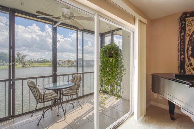 sunroom featuring ceiling fan and a water view