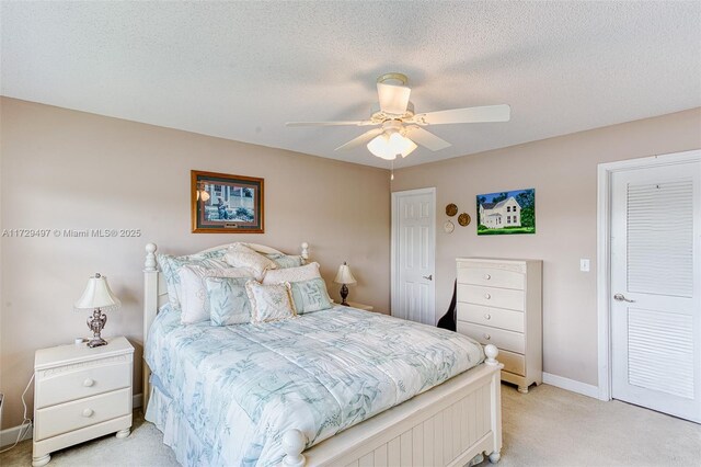 bedroom featuring ceiling fan, a textured ceiling, and light carpet