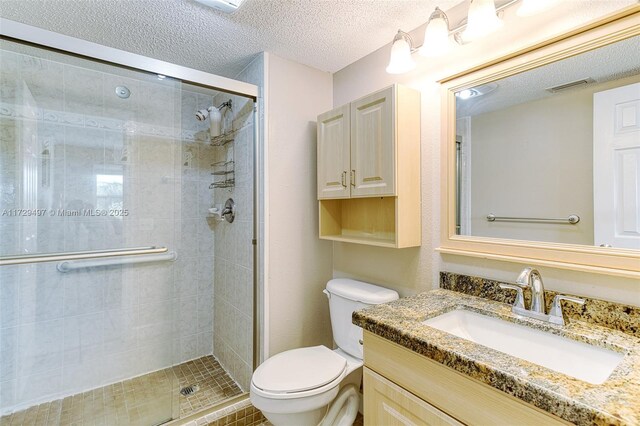 bathroom with a textured ceiling, toilet, an enclosed shower, and vanity