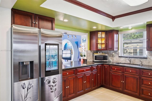 kitchen with appliances with stainless steel finishes, dark stone counters, decorative backsplash, sink, and ornamental molding