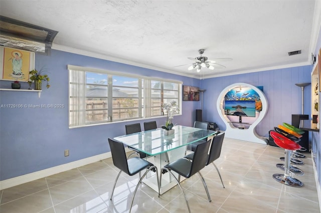 tiled dining area featuring ceiling fan, a textured ceiling, and ornamental molding