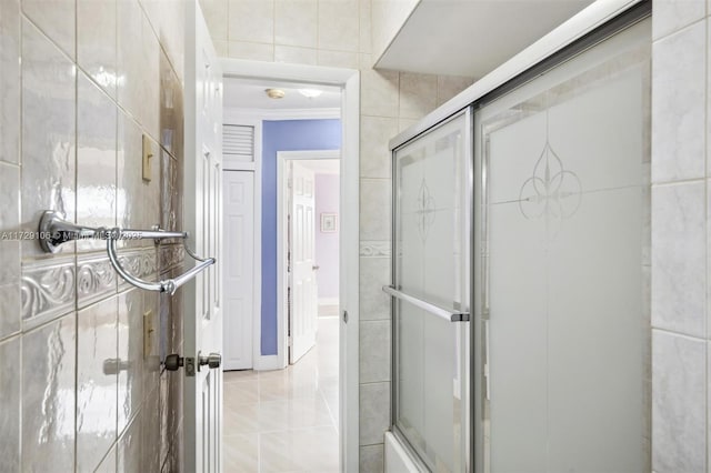 bathroom featuring tile patterned floors, enclosed tub / shower combo, and tile walls