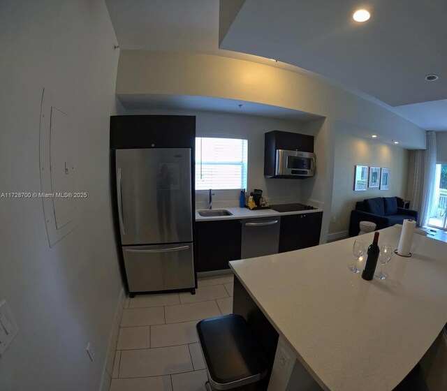 kitchen featuring sink, light tile patterned floors, a kitchen bar, a center island, and stainless steel appliances