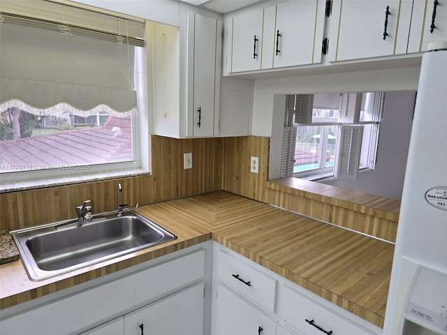 kitchen with sink, a wealth of natural light, white cabinets, and white refrigerator