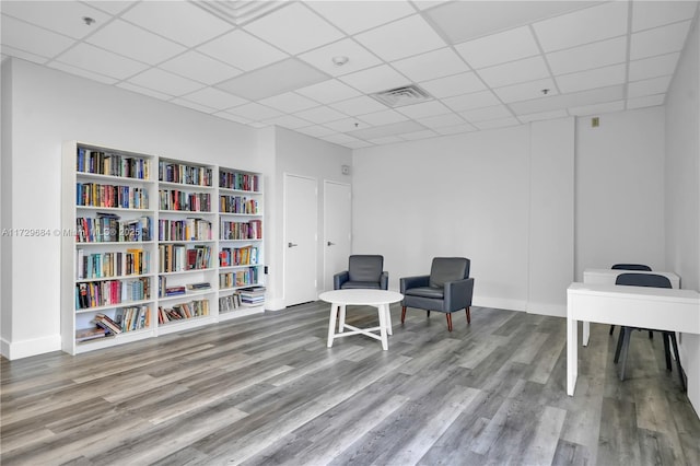 living area featuring visible vents, baseboards, wood finished floors, and a drop ceiling
