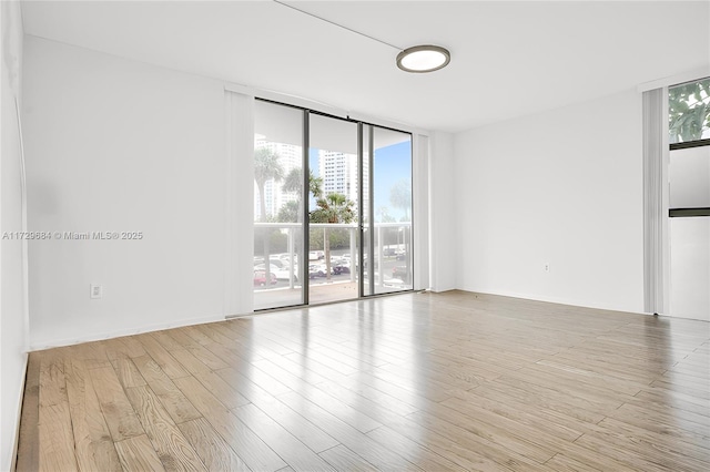 empty room with wood finished floors and floor to ceiling windows