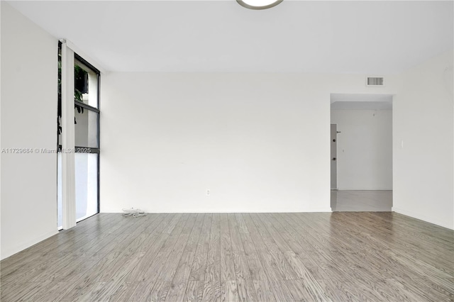 unfurnished room featuring baseboards, wood finished floors, and visible vents