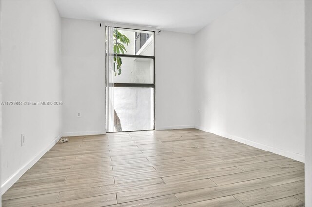 unfurnished room featuring baseboards and light wood-type flooring