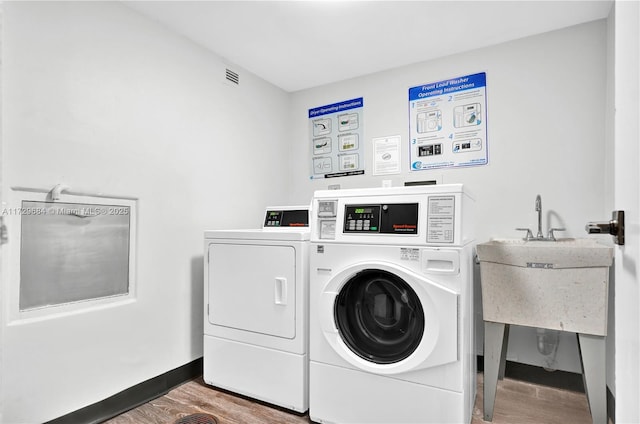 shared laundry area with baseboards, wood finished floors, visible vents, and independent washer and dryer