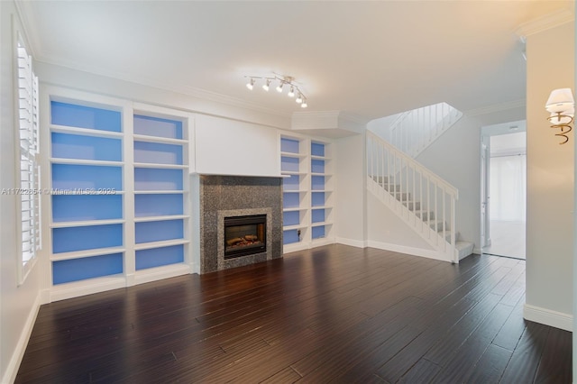 unfurnished living room featuring hardwood / wood-style floors, built in features, crown molding, and a fireplace