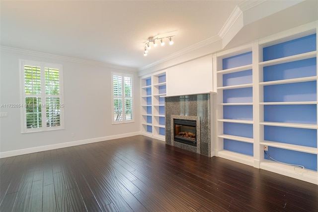 unfurnished living room featuring dark wood-type flooring, built in shelves, crown molding, and rail lighting