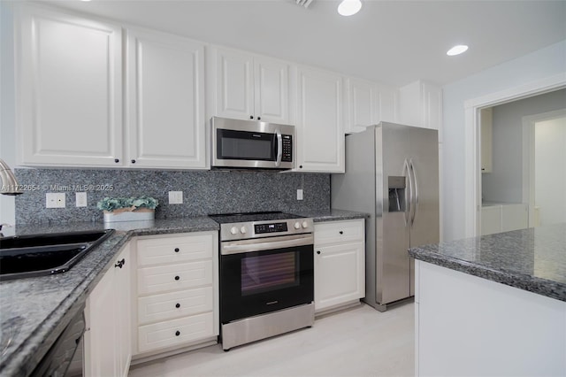 kitchen with white cabinets, tasteful backsplash, and appliances with stainless steel finishes